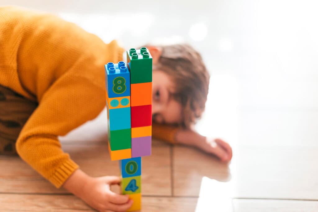 A young child concentrating on stacking colorful building blocks