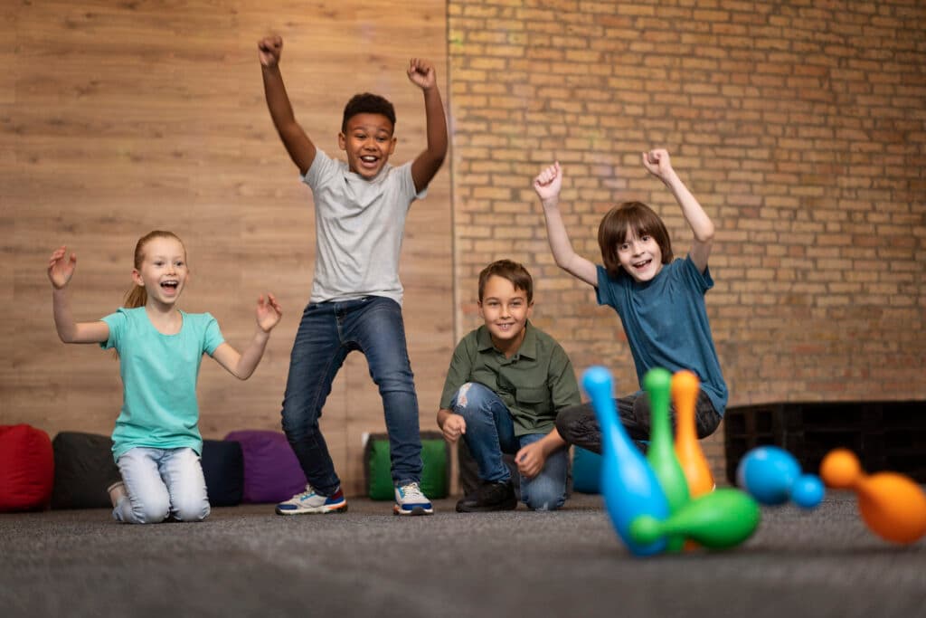 Smiling kids playing a bowling game together during a social group activity